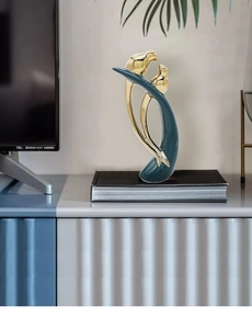 Detail of luxury ceramic lovebird statues in peacock green and gold on books