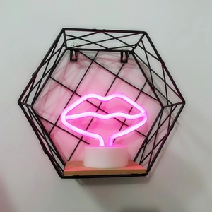 Pink lips neon lamp with white circular base on a minimalist black metal wall shelf
