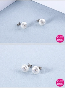 Macro shot of minimalist cross embossed white pearl earrings with polished steel posts