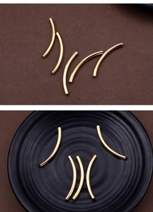 Close-up of curved golden stainless steel tube charms for DIY jewelry making