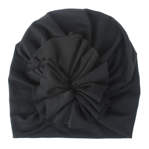 Close-up of baby turban hat featuring a large pleated fabric flower on black cotton knit