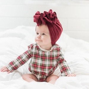 Close-up of baby turban hat featuring a large red pleated flower on elastic cotton fabric