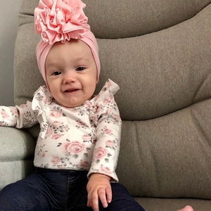 Close-up of a pink baby knit hat featuring a large 3D pleated flower decoration