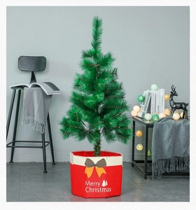 Detail of green artificial Christmas tree in a red fabric base bag with Merry Christmas text