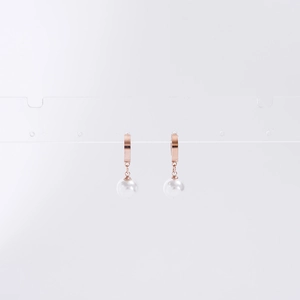 Détail de boucles d'oreilles en titane or rose avec perles blanches sur un support