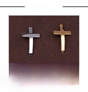 Macro view of stainless steel cross charms in gold and silver with double loop connectors