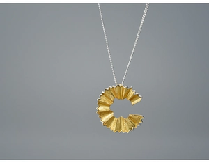 Macro shot of creative gold pencil shavings pendant with delicate silver chain necklace