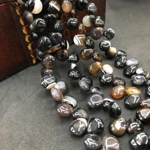 Macro shot of smooth black and brown banded agate teardrop beads for jewelry crafting