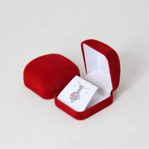 Macro shot of red velvet jewelry boxes with a silver necklace featuring a pink gemstone