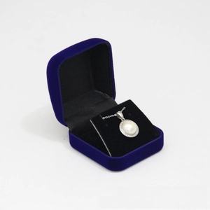 Detail of dark blue velvet jewelry box with pearl necklace on black lining