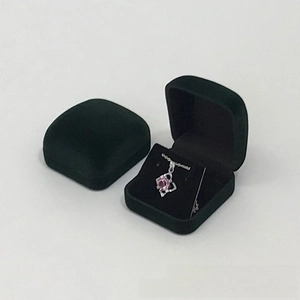 Macro detail of dark green velvet jewelry box showing silver pink diamond necklace inside