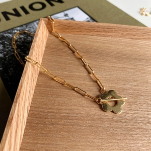 Detail of 925 sterling silver gold flower chain necklace on a light wooden tray