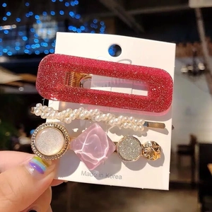 Close-up of three-piece hair clip set with pearls and glitter on a card holder