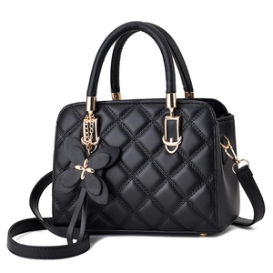 Classic black quilted leather crossbody bag with bow charm and gold hardware on white background