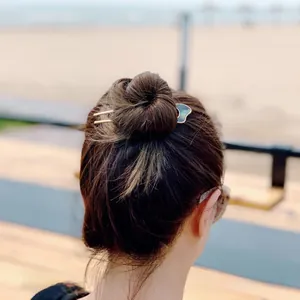 Close-up of golden U-shaped metal hair fork with green shell cloud motif in hair