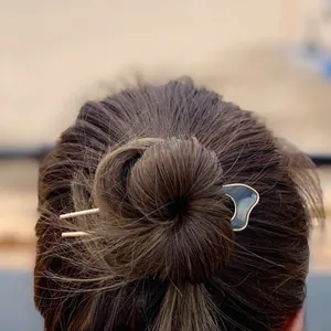 U-shaped gold hair pin with shell inlay detail worn in a professional bun hairstyle