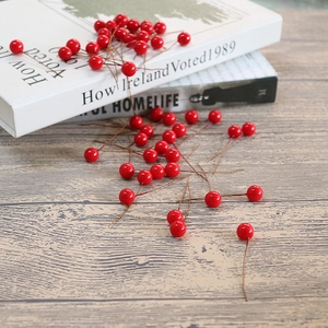 Artificial red holly berries on decorative books and light wood background for Christmas decor