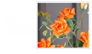 Detail of vibrant orange artificial roses with natural green leaves and brown stems