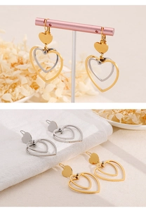 Close-up of dual-layer heart-shaped pendant earrings in polished gold and silver finishes