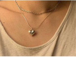 Close-up of double layered 925 silver heart necklace on neck featuring snake bone chain