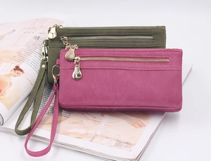 Detail of dark green and rose long wallets with matte texture and gold teardrop zippers