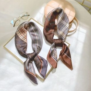 Flat lay of silk-like square scarves with geometric prints on a gold frame and wood base