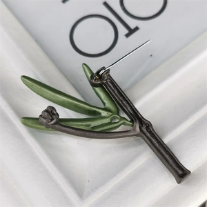 Macro view showing the metal pin back and green enamel leaf details of the olive branch brooch