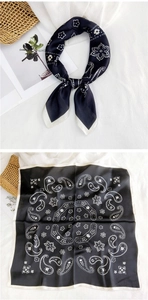 Macro detail of square silk scarf with black and white paisley pattern tied in a bow