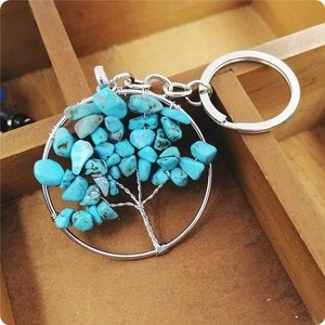 Detailed view of Tree of Life keychain with blue turquoise stones on a wooden background