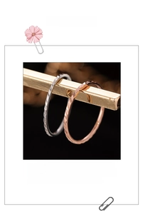 Dettaglio di anelli a treccia in argento e oro rosa su un supporto per gioielli sobrio