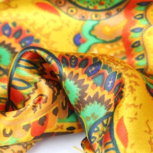 Close-up of golden paisley satin scarf showing smooth twill texture and vibrant print detail