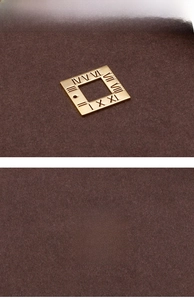 Macro detail of gold square titanium pendant with hollow Roman numeral engraving