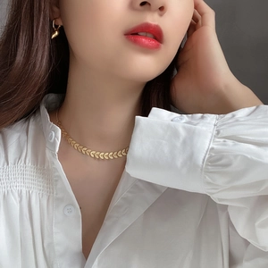 Close-up of golden leaf pattern necklace and stud earrings set on a female model