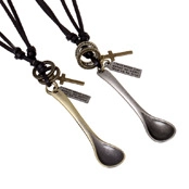 Detail of bronze and silver spoon pendants with engraved metal tags on black cords
