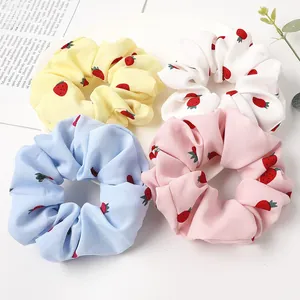 Close-up of four floral strawberry print scrunchies in yellow, white, blue and pink