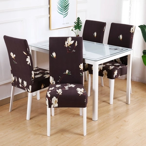 Detail of four dark brown elastic chair covers with white magnolia floral print on dining chairs