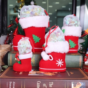 Detailed view of red flocked Christmas boot candy bags with white plush trim and mesh netting