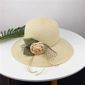 Detailed close-up of beige straw hat with delicate cloth flower and mesh ribbon lace