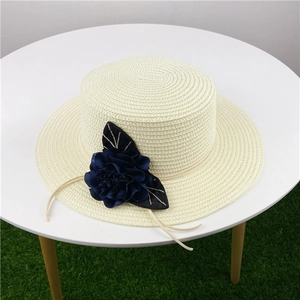 Dettaglio di un cappello di paglia a tesa larga con un grande fiore blu sull'erba