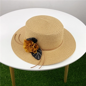Dettaglio cappello di paglia con fiori gialli e foglie di paillettes per il sole