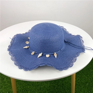 Chapeau de soleil bleu en paille avec coquillages et bord ondulé pour la plage