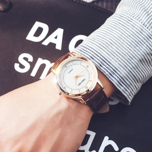 Montre classique en or rose avec cadran blanc et bracelet en cuir marron au poignet
