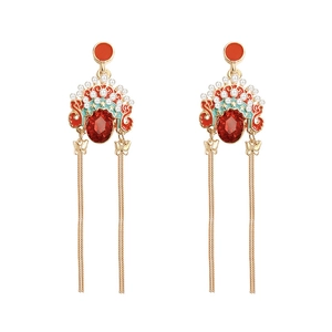 Ethnic style long tassel earrings with red gemstones and pearl accents on white background