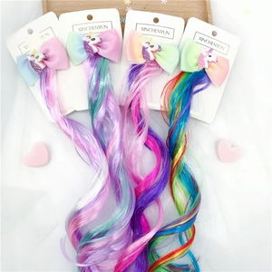 Detail of four colorful unicorn hair bow clips with long rainbow gradient wigs on card