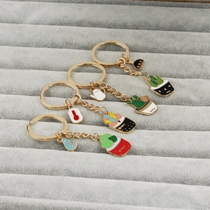 Detailed view of four enamel cactus and succulent keychains with small garden tool charms