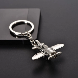 Macro shot of silver propeller aircraft keychain with polished metal finish on dark surface