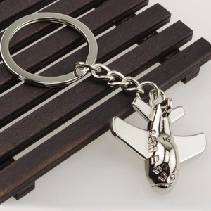 Close-up of a silver fighter jet metal keychain on a dark wooden background