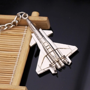 Close-up of a silver fighter jet keychain with detailed metallic textures on a stand