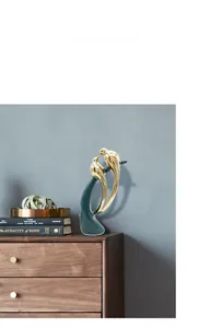 Detail of luxury emerald green ceramic birds with gold accents on a modern wooden cabinet