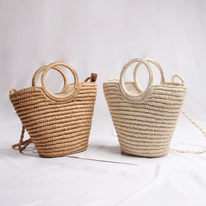 Detail view of two handmade straw bags in beige and cream white with round handles